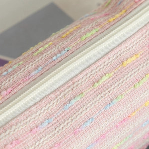 Detail shot of pink tweed pencil case featuring colorful woven texture and white zipper
