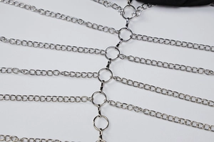 Detail van de zilveren metalen lichaamsketting met schakels en centrale ringverbinder