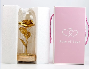 Detail of gold foil rose in glass dome with LED lights, pink gift box and foam packaging