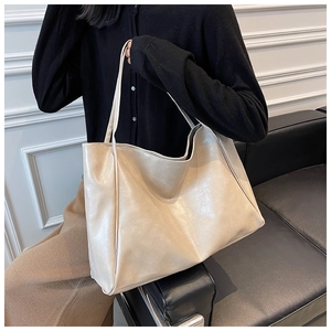 Detailed view of large cream PU leather tote bag with glossy finish on a shoulder
