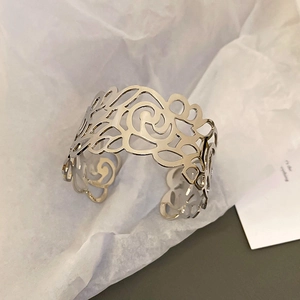 Top view of silver teardrop open bangle showing intricate hollow patterns and adjustable design