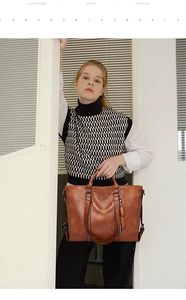 Dettaglio di grande borsa tote vintage in pelle marrone con cerniere funzionali e anelli metallici