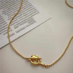 Nahaufnahme der goldenen Kugelkette mit modischem T-Verschluss auf einer Karte