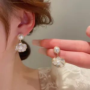 Close-up of elegant camellia drop earrings with gold metal base and pearl accents