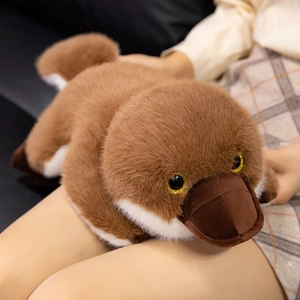 Fluffy platypus plush toy with brown fur and realistic beak being held in a cozy setting