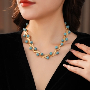 Detail of vintage gold wave necklace with turquoise beads and crystals on a model