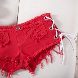 Dettaglio degli shorts in denim rosso con bordi sfilacciati e lacci laterali con anelli