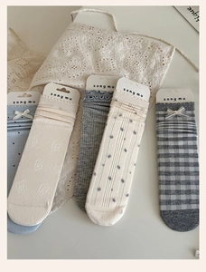 Detail of five blue and beige cotton socks featuring bows and lace embroidery