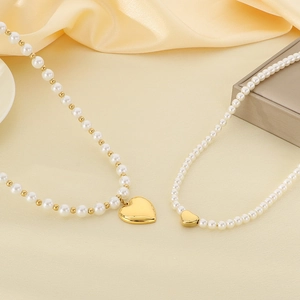 Detailed view of pearl beaded necklaces with gold heart pendants on cream silk fabric