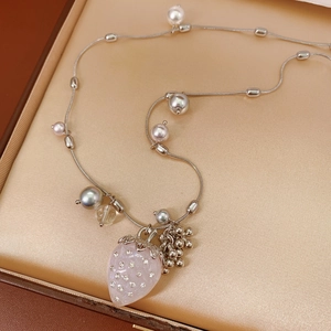 Close-up of sparkling strawberry pendant with silver leaves and pearls on snake chain