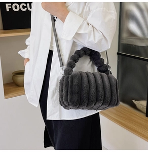 Plush grey faux fur bag shown on model featuring unique fuzzy ball handle and shoulder strap