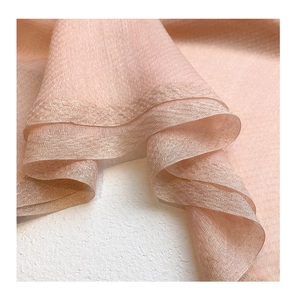 Detail of pink silk wool fabric with subtle metallic shimmer and premium hemmed edges