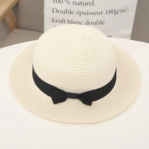 Close-up of cream flat top straw hat featuring a chic black ribbon bow detail