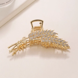 Close-up of golden wheat ear hair claw clip with sparkling rhinestones and metal finish