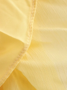 Detailed close-up of yellow pleated fabric texture with neat double-row stitching detail