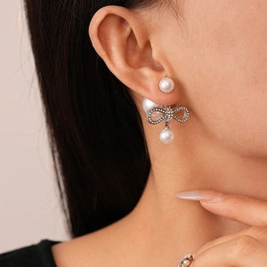 Detailed view of silver bow earrings with layered pearls and sparkling rhinestones