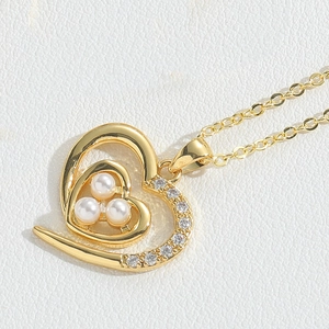 Macro detail of golden heart pendant featuring three pearls and sparkling zircon stones