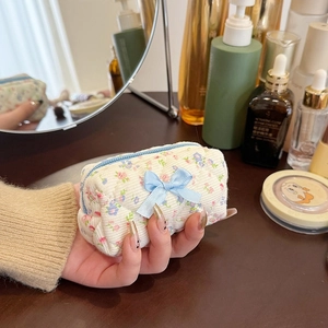 Mini floral cotton makeup bag with quilted pattern and blue ribbon bow in hand