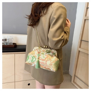 Model wearing vintage silk embroidery bag with golden chain and green tassel detail