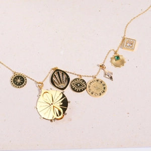 Detailed flat lay of gold zircon charms with eye and sun motifs on textured paper