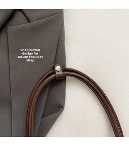 Detail of dark brown leather strap with silver snap button and strap holder on a bag
