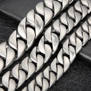 Close-up of matte silver Cuban links with brushed texture on black leather background