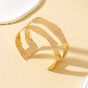 Close-up of golden wide open cuff bangle with double-layered hollow design and hammered texture