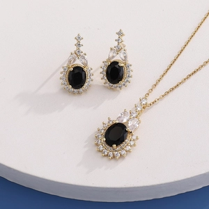 Detailed close-up of golden necklace and earrings with black oval gems and white crystals