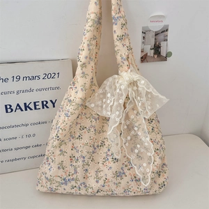 Detail of floral canvas tote bag featuring a white lace bow and sweet cottagecore style