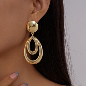 Close-up of golden geometric hollow teardrop earrings worn by a model in profile view