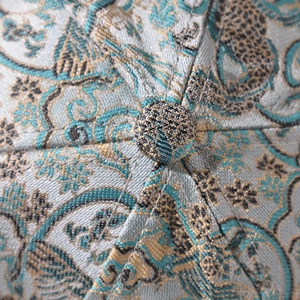 Detail of vintage blue jacquard fabric on a baseball cap with golden embroidery