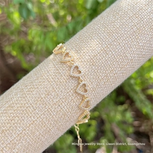 Detail of 18K gold plated heart link bracelet with zircon inlay on a linen display