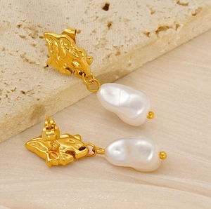 Close-up of vintage baroque pearl earrings with gold irregular metal base on silk texture