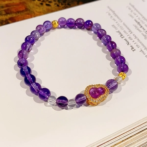 Detailed shot of purple crystal beaded bracelet with a heart-shaped gold pendant