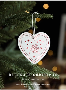 Wooden heart Christmas ornament with red snowflake print hanging on a festive tree branch