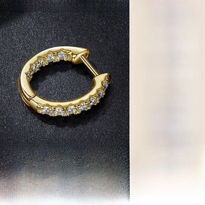 Detail of gold-plated silver earrings with pavé set moissanite stones on black background