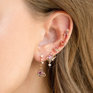 Close-up of golden galaxy earrings featuring pink moon and purple star zircon stones