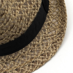 Macro detail showing woven straw texture and black grosgrain ribbon on the fedora hat