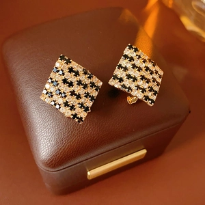 Gros plan de boucles d'oreilles losange avec motif en damier sur une boîte en cuir