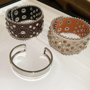 Détail de bracelets en cuir avec strass et rivets à côté d'une manchette en argent poli
