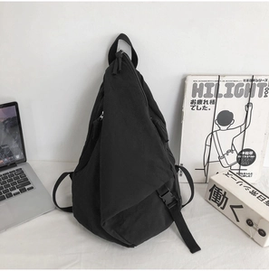 Detail view of black canvas backpack featuring irregular geometric cut and matte buckle