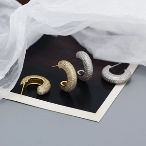 Macro shot of silver and gold paved diamond hoop earrings on minimalist background