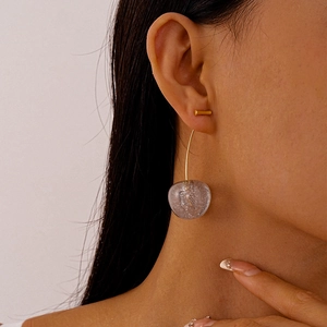 Close-up of model wearing gold long drop earrings with silver glitter resin balls