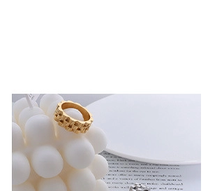 Macro view of gold woven texture ring displayed on white bubble candle with soft lighting