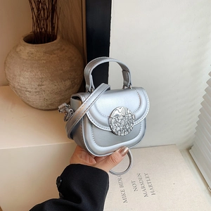 Detail of silver metallic mini handbag featuring a unique round cracked decorative buckle