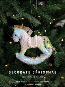 Close-up of a rocking horse Christmas ornament on a tree with warm glowing lights