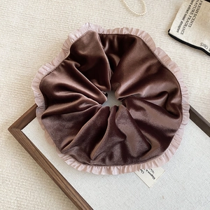 Macro detail of brown velvet scrunchie with delicate pink tulle ruffle edge
