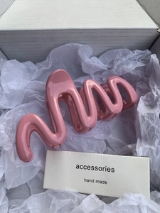 Close-up of pink jelly-colored wavy hair claw clip in a minimalist white gift box