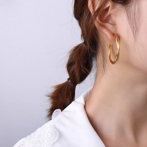 Golden double twist hoop earrings in 18k gold plated titanium steel worn by model