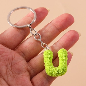 Detailed close-up of a green letter U keychain with intricate rose floral texture
